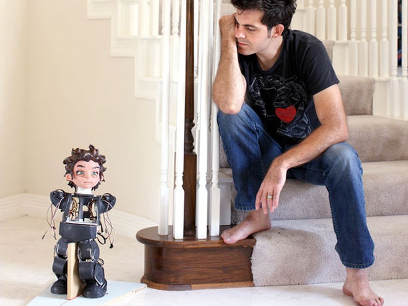 Roboticist David Hanson seated beside one of his humanoid robots